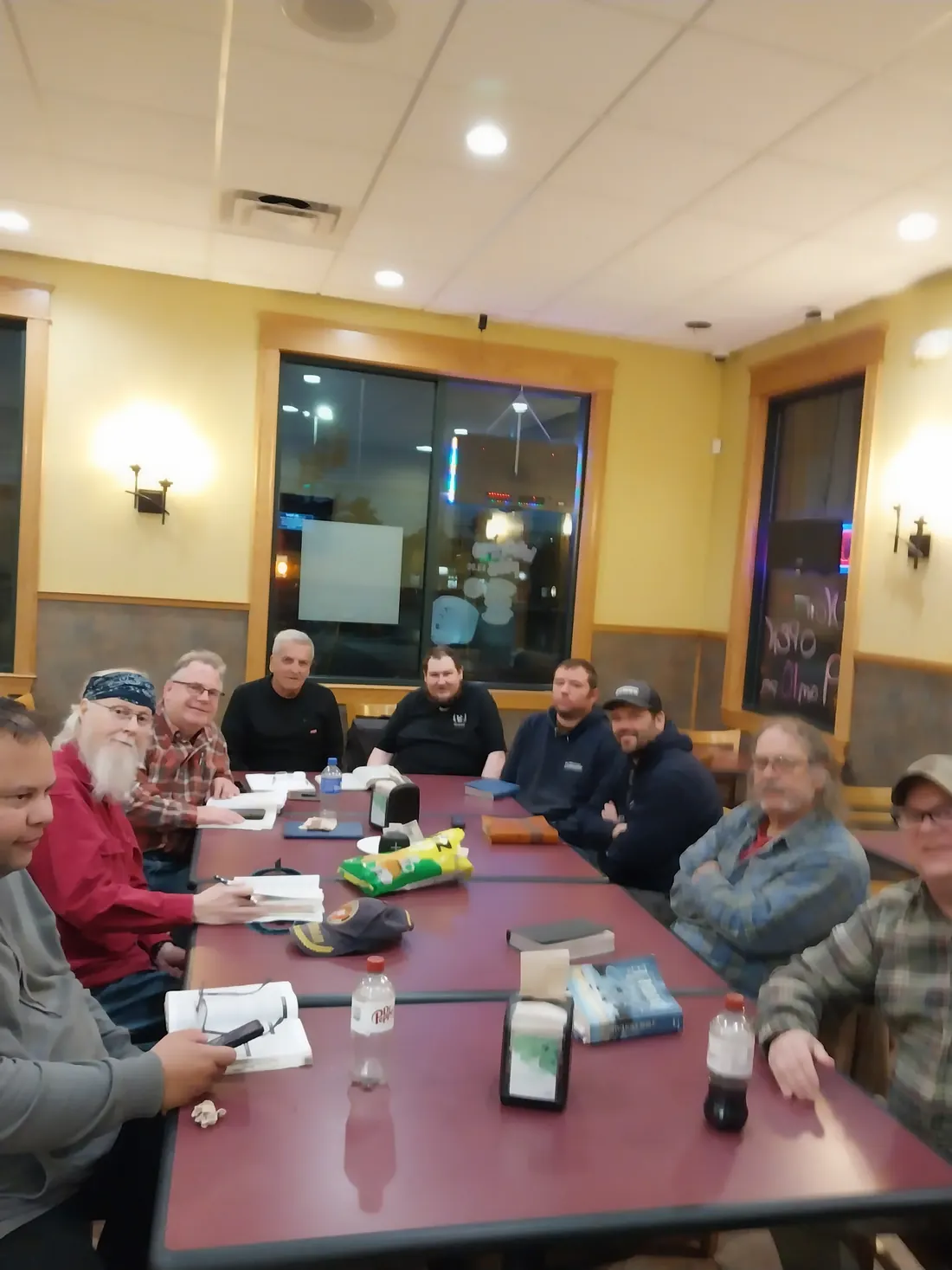 A group of men gathered around a table with Bibles open during a weekly meeting